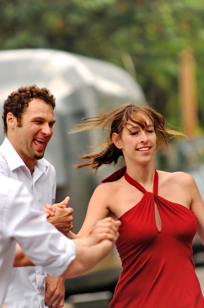 Un couple danse la salsa avec un grand sourire.